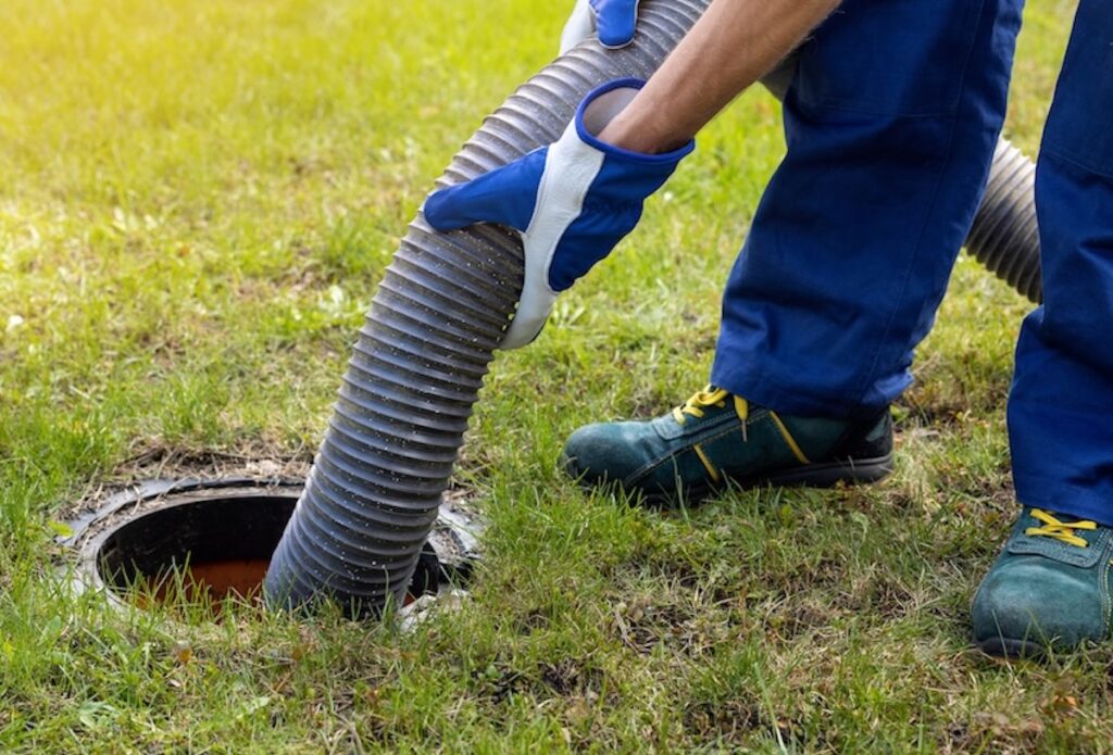 man pumping out house septic tank. drain and sewage cleaning service.