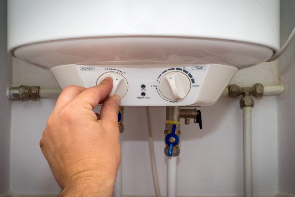 Man turns on the switch on control panel of home electric water heater