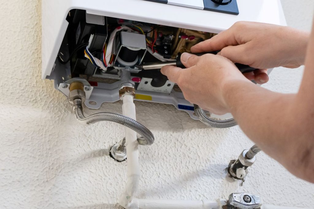 Professional technician using a screwdriver to service and maintain a tankless gas water heater