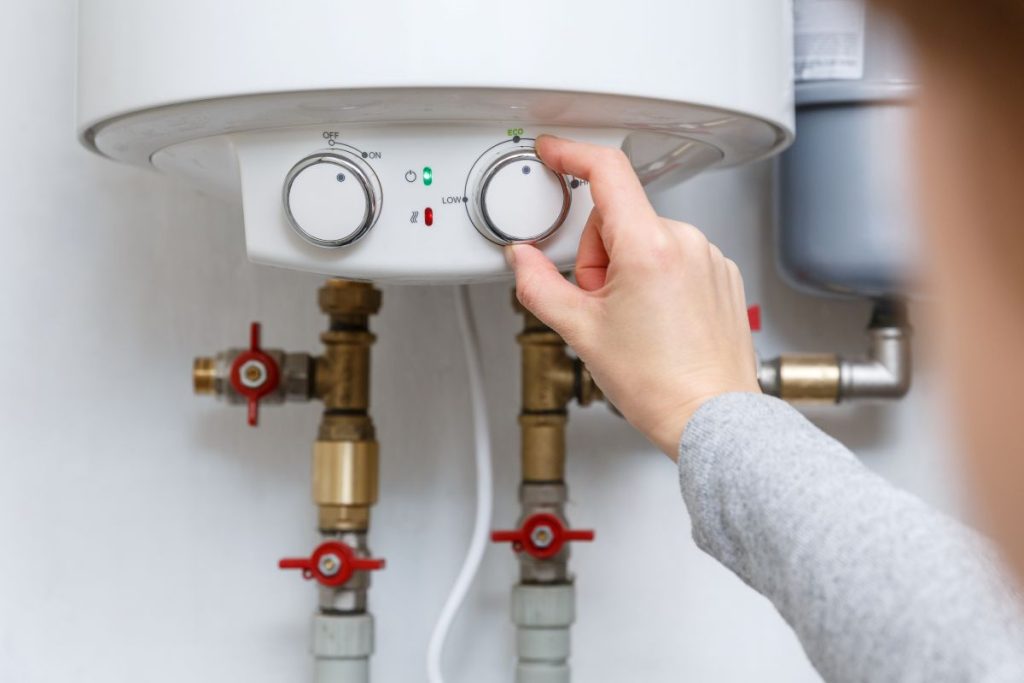 hand puts thermostat of electric water heater (boiler) in economy mode.