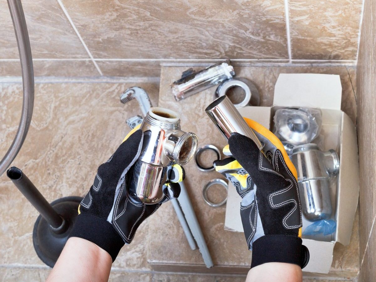 Sanitary technician repairs plumbing trap from sink in bathroom